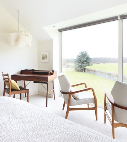 The simple, curvy wood arms and legs of mid century modern chairs stand out beautifully in a minimalist white on white room (via Houzz)